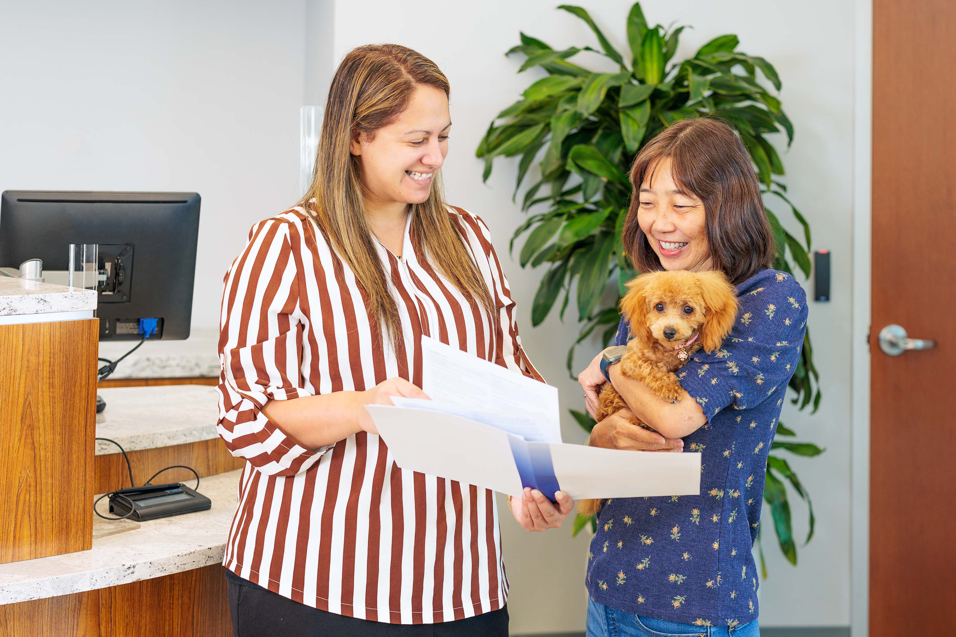 employee reviewing documents with member holding a dog